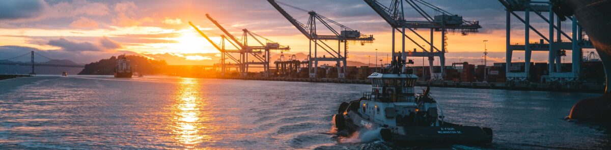 a panoramic shot of oil rigs at sea with a beautiful sunset in the background, under cloudy sky